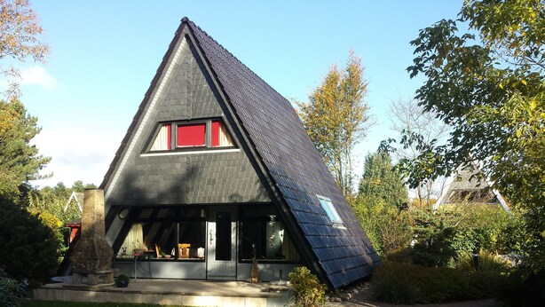 A modern house with a sloped roof, large windows, and a stone chimney. - Here you will find harmony for the soul and body, garden & house are inviting (Damp)