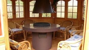 A wooden interior with a round table, wicker chairs, and a large black lamp. - Here you will find harmony for the soul and body, garden & house are inviting (Damp)
