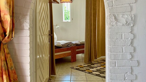 Une pièce comprenant un lit, une fenêtre et une porte donnant sur une autre pièce.