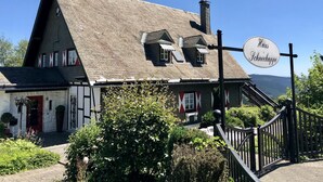 Un bâtiment traditionnel avec un toit à forte pente, une cheminée et une enseigne indiquant « Haus Schneekappe ».
