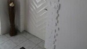 Une pièce avec un mur blanc à la texture particulière et une arche décorative.