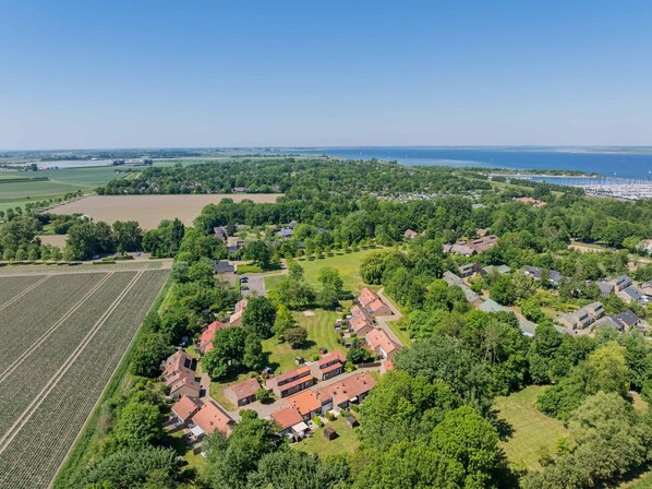 Vista aérea de una zona residencial con casas, campos verdes y un puerto deportivo con barcos.