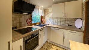 Una cocina compacta con estufa a gas, horno y ventana con cortinas.