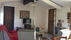 Ein Wohnzimmer mit Flachbildfernseher, einem Gemälde und einer Blumenvase.