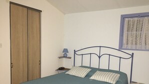 Ein Schlafzimmer mit einem Bett, einem Nachttisch, einer Lampe und einem Fenster mit Vorhängen.