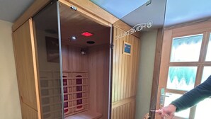 A sauna with a wooden interior, a glass door, and a control panel on the wall. - Farmhouse near the Baltic Sea (Upahl)