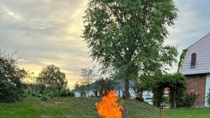 A fire pit with logs and a metal poker, surrounded by a gravel area. - Farmhouse near the Baltic Sea (Upahl)