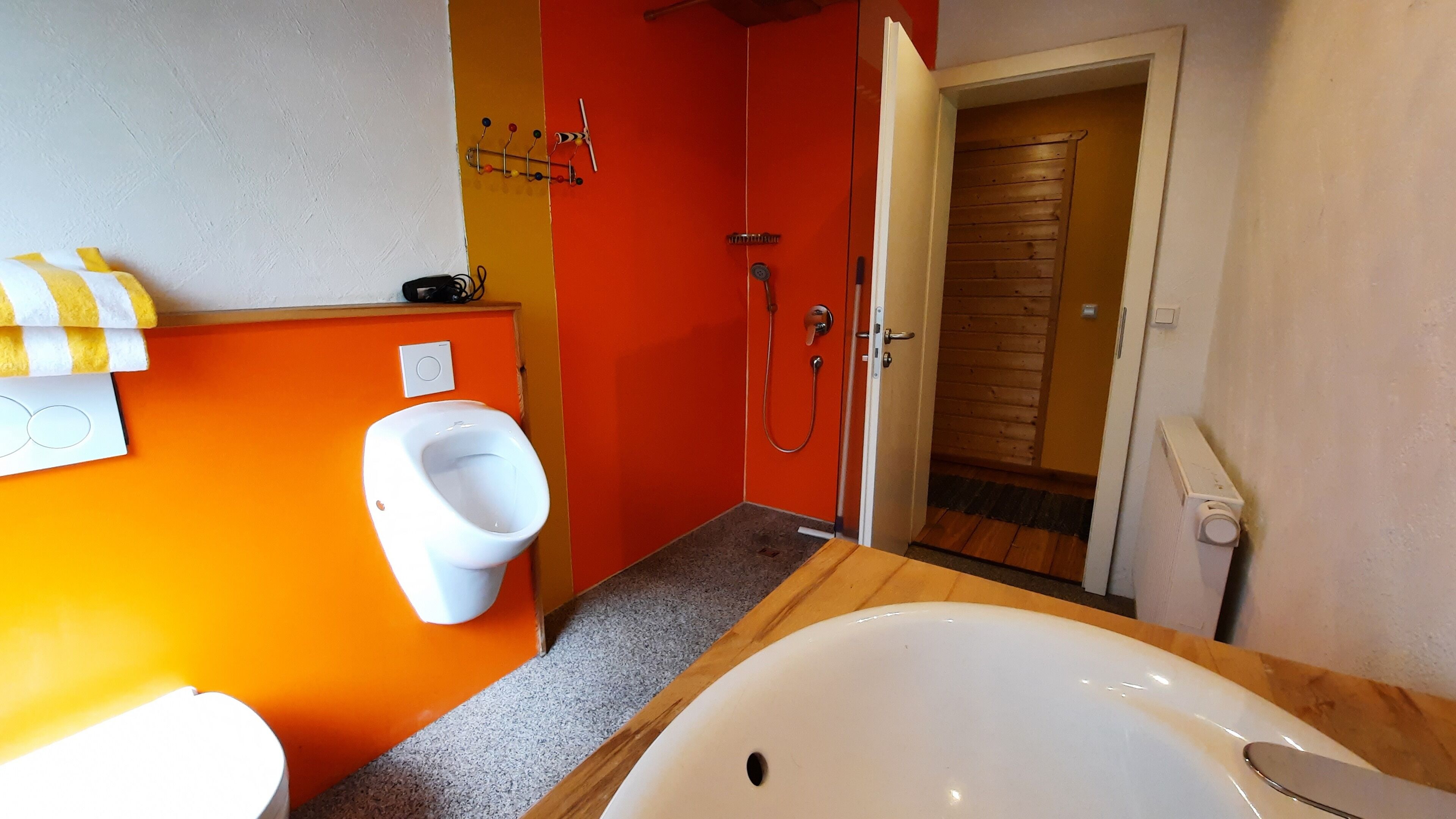 Ein Badezimmer mit einem weißen Urinal, einer Dusche und einer Badewanne.