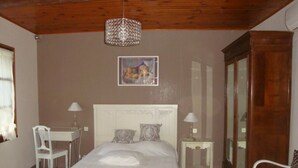 Una camera da letto con un letto, due comodini, una sedia, un lampadario e uno specchio.