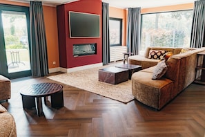 Una sala de estar moderna con chimenea, un sofá, una mesa de centro y un ventanal grande.