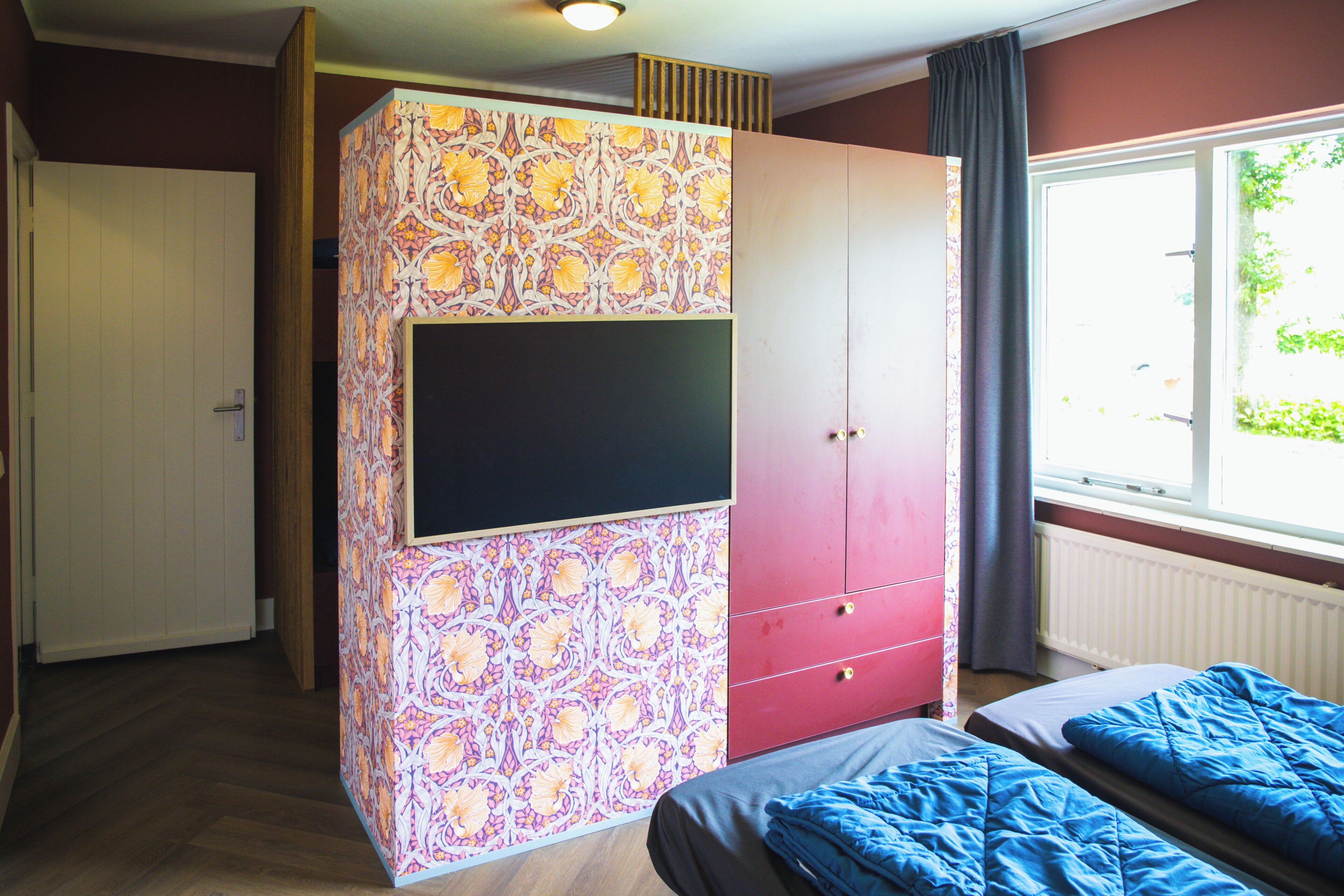 Een slaapkamer met een bed, een kledingkast, een televisie en een raam met uitzicht.