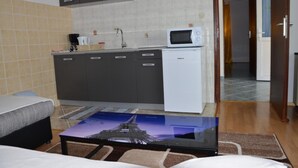 Une chambre compacte avec une kitchenette, un lit et une vue sur la Tour Eiffel par la fenêtre.
