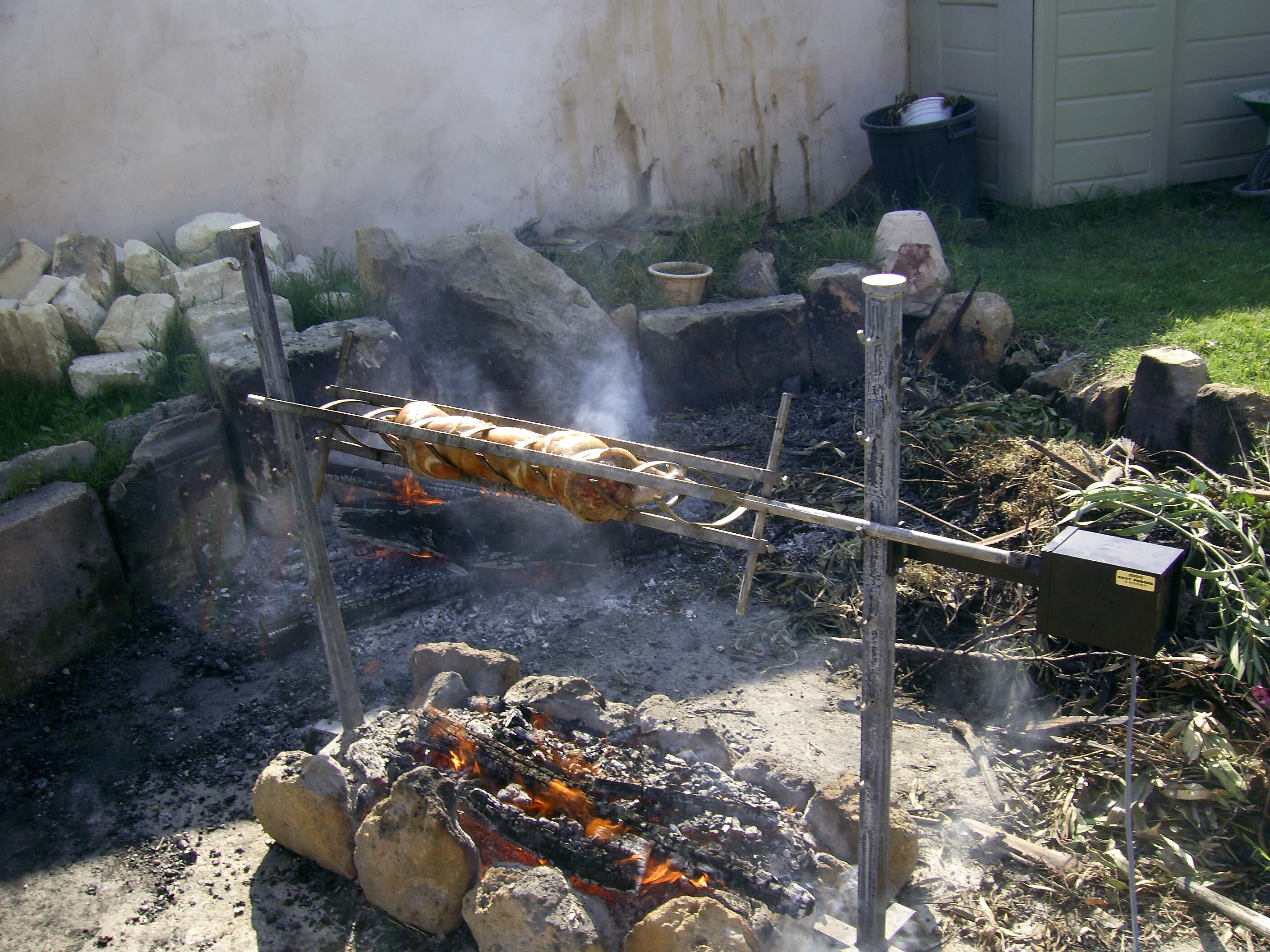 Un'attrezzatura tradizionale per cucinare all'aperto, con una rosticceria sopra un fuoco vivo.