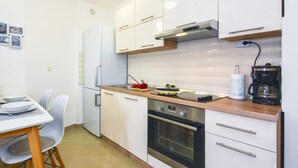 Uma cozinha moderna com armários brancos, forno embutido e cafeteira.