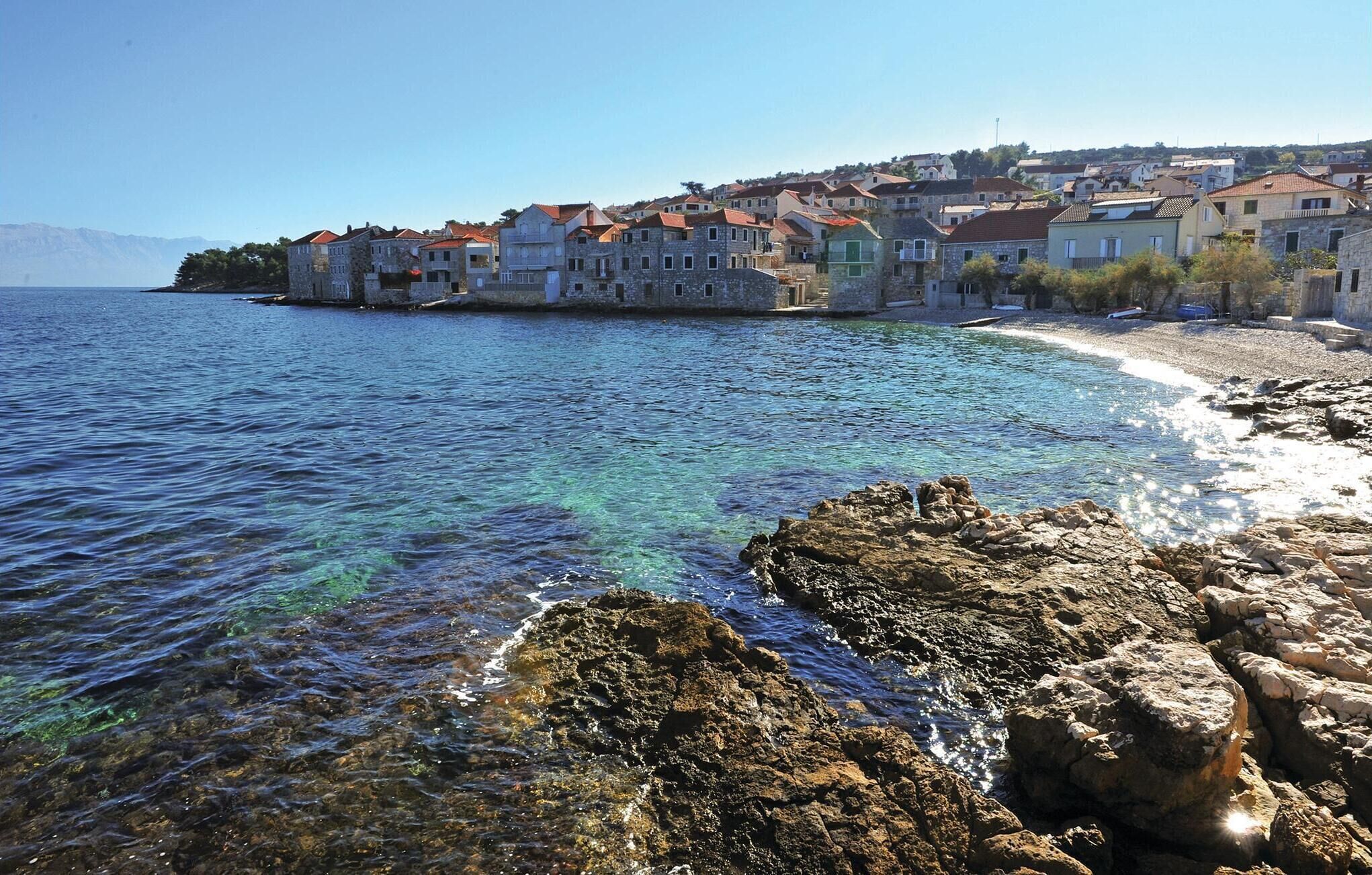 A coastal town with stone buildings, clear blue waters, and rocky shores.