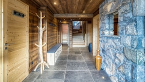 Interior de madera con pared de piedra, un banco y perchero.