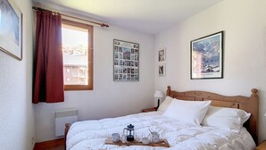 Uma cama bem arrumada com uma bandeja de itens de café da manhã, uma janela com cortinas e um pôster na parede.