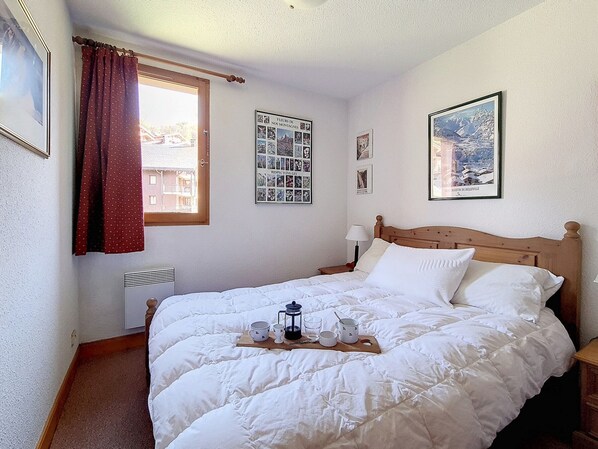 Una cama bien hecha con una bandeja de desayuno, una ventana con cortinas y un cartel en la pared.
