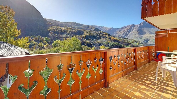 Varanda de madeira com vista para uma paisagem montanhosa.