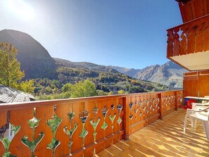 Un balcón de madera con vistas a un paisaje montañoso.