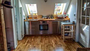 Eine kleine Küche mit Holzboden, integriertem Backofen, Spüle und einer Essecke.