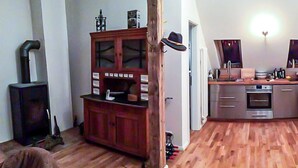 Ein Zimmer mit Holzboden, einem Schrank mit Glastüren, einem Kamin und einer Küchenzeile mit Spüle und Backofen.
