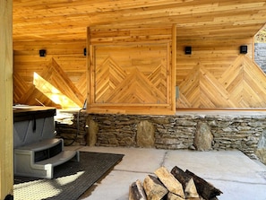 Interior de una cabaña de madera con pared de piedra, chimenea y panel de pared con patrón de espiga.