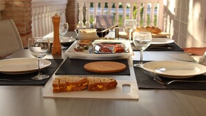 A table set for a meal with plates, glasses, a bread basket, and a bottle of water.