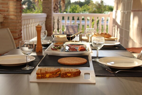 Una mesa servida para una comida, con platos, vasos, una cesta de pan y una botella de agua.