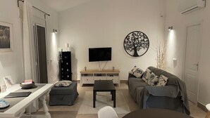 A modern living room with a flat-screen TV, a round wall decoration, a sofa, a dining table, and a sideboard.