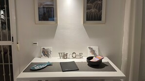 A reception desk with a 'Welcome' sign, framed artwork, a 'Beach' placard, a black folder, and a bowl with magazines.