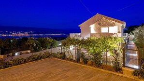 A two-story house with a balcony, a paved driveway, and a view of a cityscape and mountains in the background. - Gorgeous home in Polje (Polje)