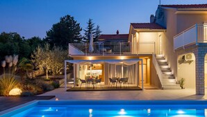 A modern two-story house with a swimming pool, outdoor dining area, and a staircase leading to a balcony. - Gorgeous home in Polje (Polje)