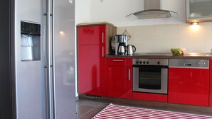 Eine moderne Küche mit roten Schränken, Edelstahlgeräten und einer Kaffeemaschine.