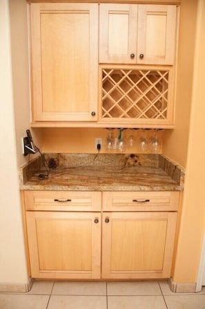Compact kitchen with light cabinetry, wine rack, and granite countertop.