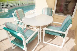 A patio with a round table and four chairs, each with striped cushions. - Ly105644 - Indian Ridge - 4 Bed 2 Baths Villa (Kissimmee)