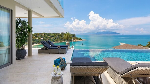 Un balcon avec vue sur la mer, des chaises longues et une petite piscine.