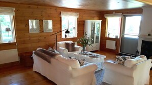 A cozy living room with a wooden interior, white sofas, a coffee table, and a fireplace.