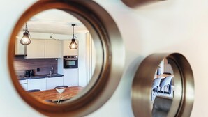 Eine moderne Küche mit Pendelleuchten, ein Essbereich mit einem Holztisch und ein Blick durch einen runden Spiegel.