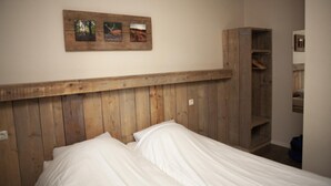 Ein Schlafzimmer mit einem hölzernen Kopfteil, einem Bett mit weißer Bettwäsche und einem Holzbodenregal.
