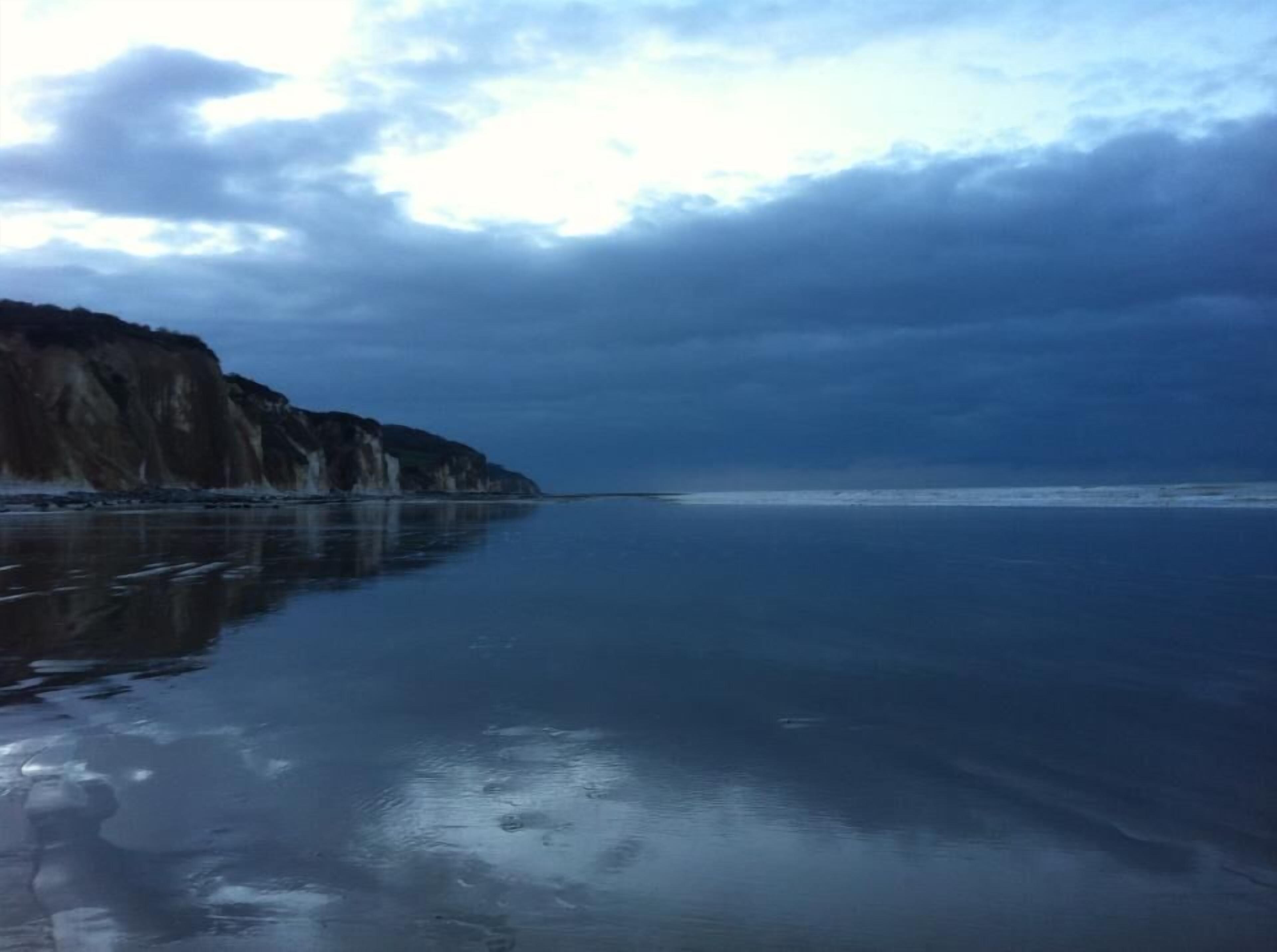 A coastal landscape with cliffs and a calm sea.