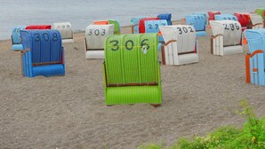 Des chaises de plage, chacune portant un numéro, sont disposées sur une plage de sable.