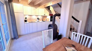 Une cuisine moderne avec des meubles blancs, une table en bois et un fourneau noir.