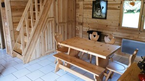 A wooden interior with a wooden table and benches, a framed picture on the wall, and a window with a view of greenery. - Typical Savoyard chalet, independent, warm and cozy (Thônes)