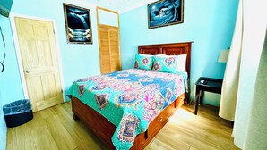 A bedroom with a wooden bed, a ceiling fan, and two framed pictures on the wall. - Queen apartment with generator, washing machine & patio furniture for relaxation (Nassau)