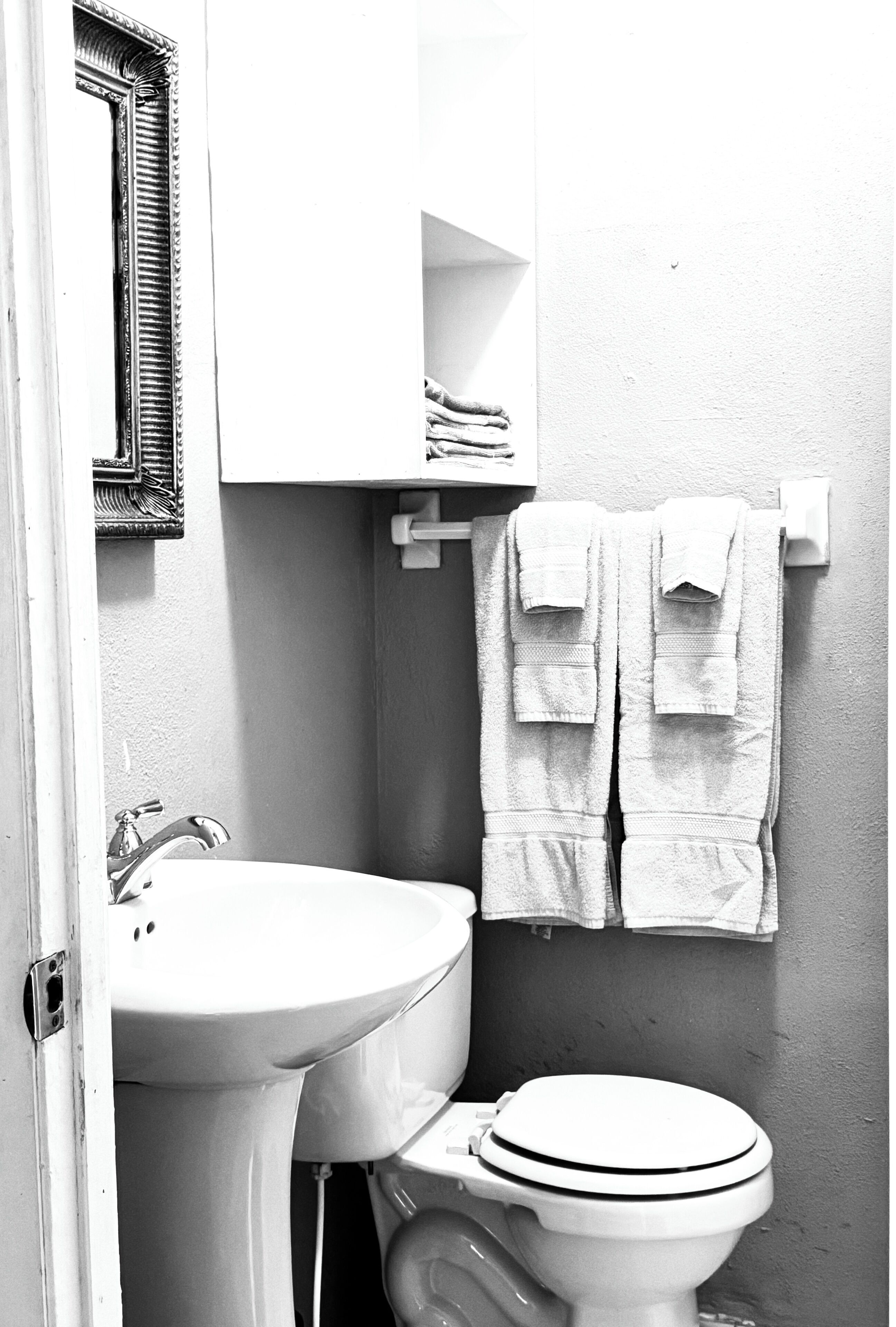 Een badkamer met een wastafel, toilet en een handdoekrek met handdoeken.
