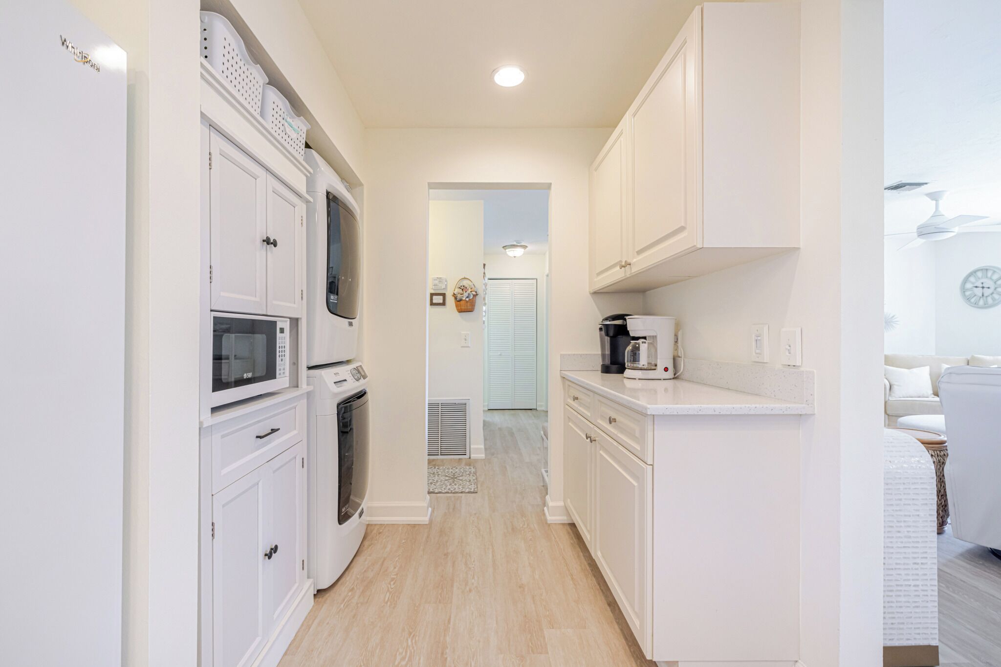 A narrow kitchen with white cabinets, a microwave, and a coffee maker.
