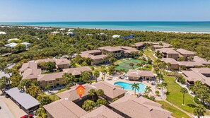 A resort with multiple buildings, a swimming pool, and a beach view.