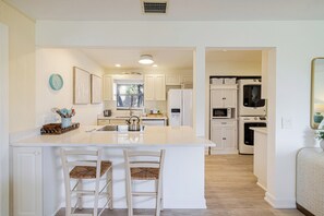 A kitchen with a central island, white cabinetry, and a view into the dining area.