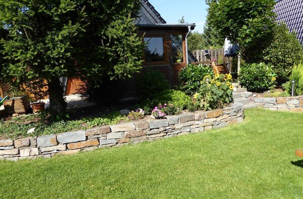 Enjoy serene surroundings in our beautifully maintained garden, complete with lush greenery and a wooden deck for outdoor relaxation.
